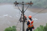 Ilustrasi banjir bandang melanda Sumatera Utara, dengan tim teknisi Telkomsel bekerja keras di lapangan memperbaiki infrastruktur jaringan yang rusak.