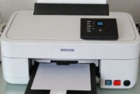Ilustrasi printer Epson L6290 yang sedang mencetak dokumen. Sorot bagian bantalan tinta limbah pada printer.