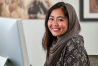 Seorang wanita tersenyum saat mengedit foto di PC dengan Ulead PhotoImpact.